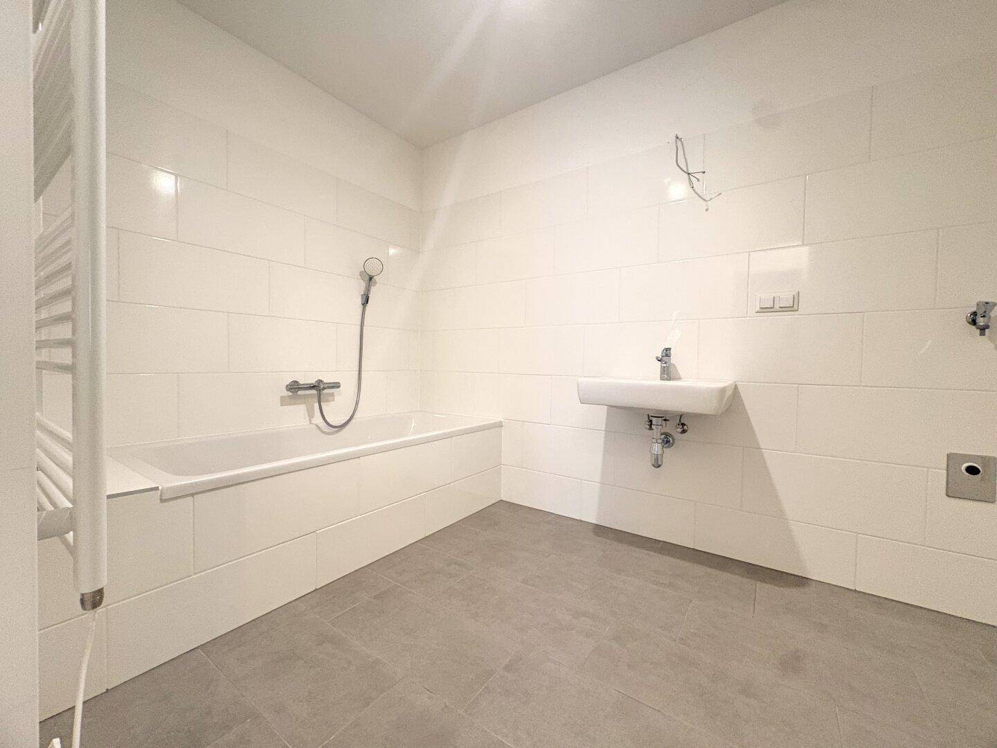 Modernes Badezimmer mit Badewanne, Waschbecken und weiß gefliesten Wänden.