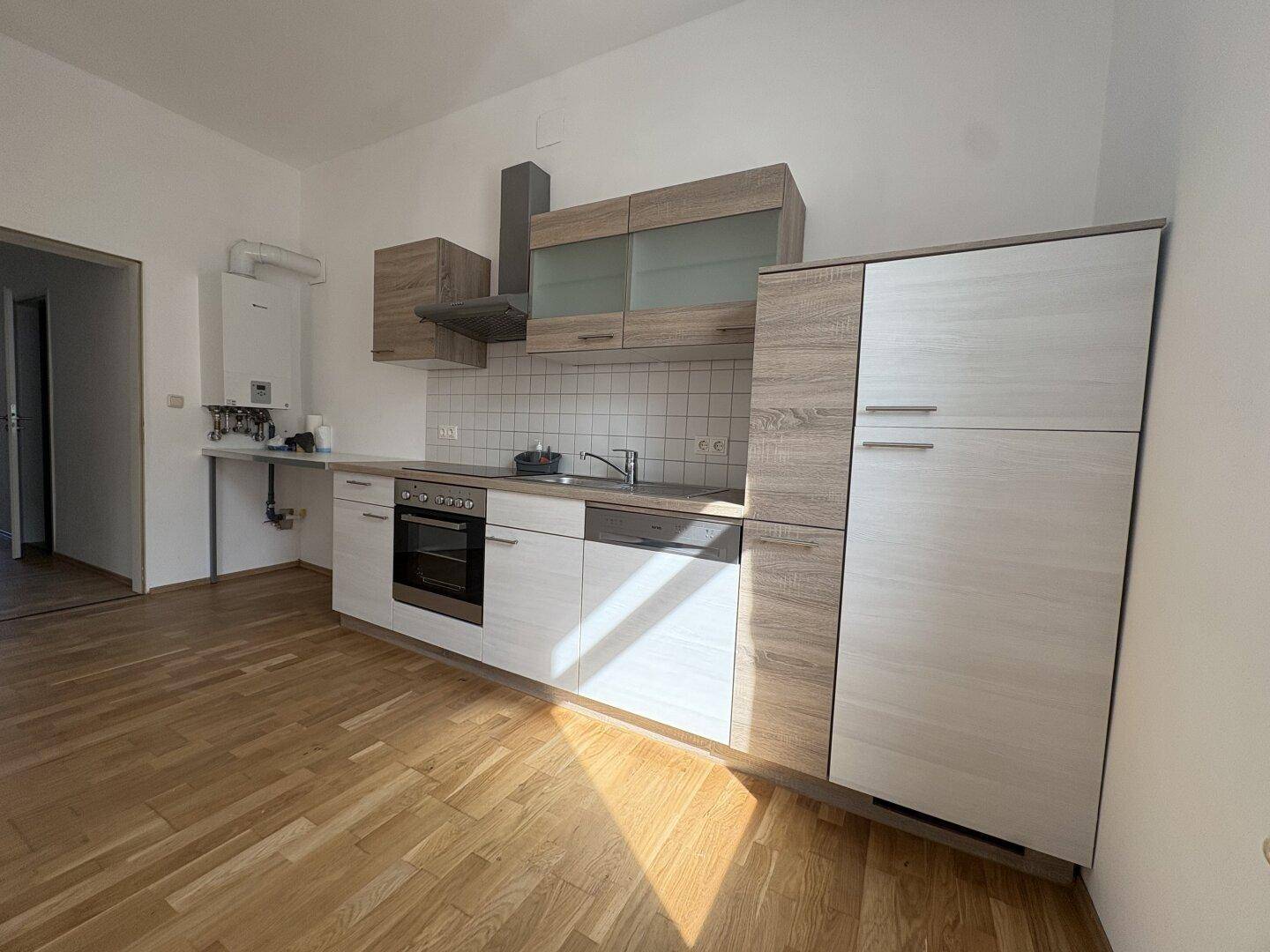Moderne Einbauküche mit hellen Fronten, Holzoptik und integrierten Geräten, sehr funktional.