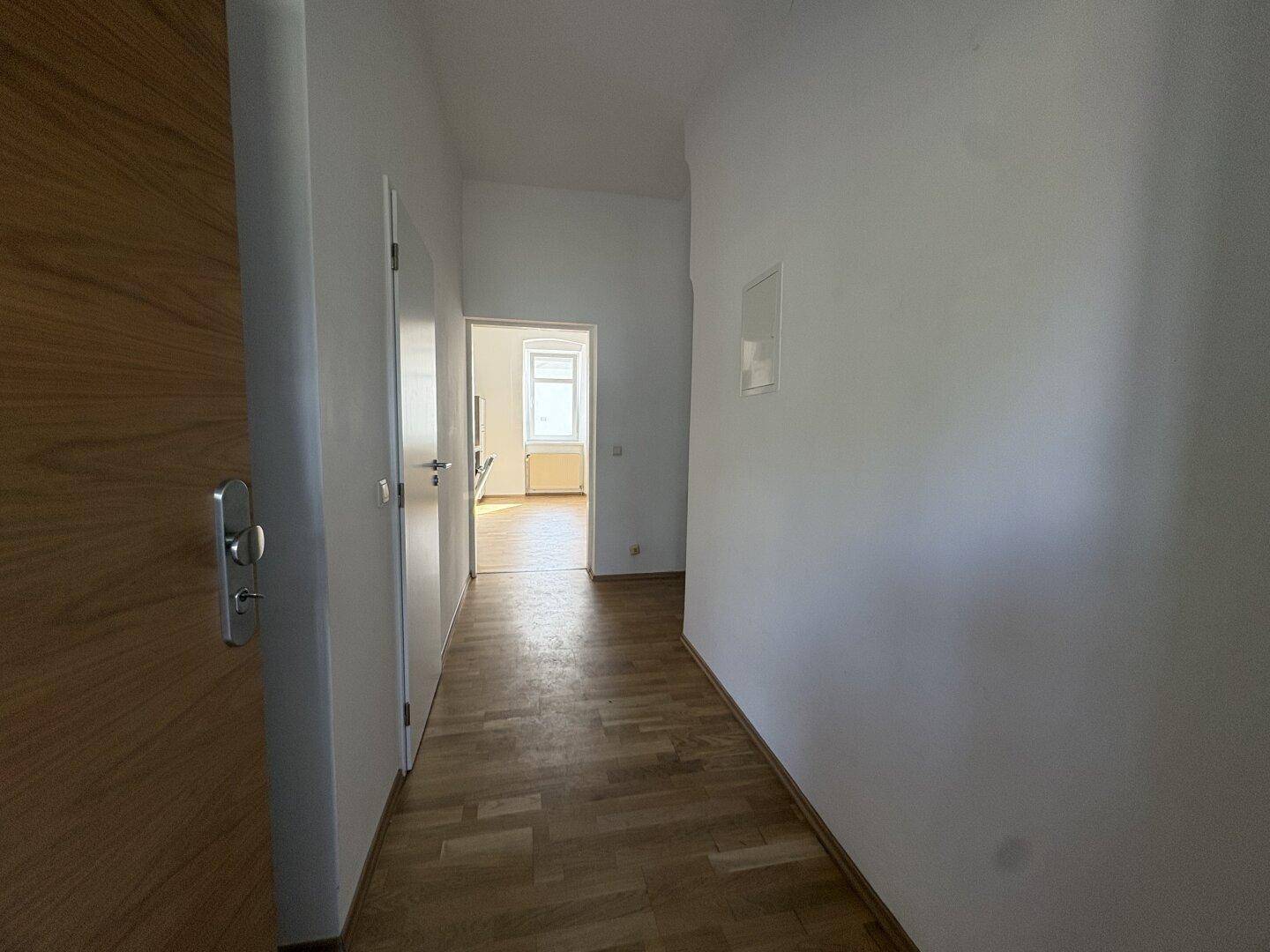 Heller Flur mit Holzparkettboden, der zu weiteren Zimmern führt und viel Tageslicht bietet.