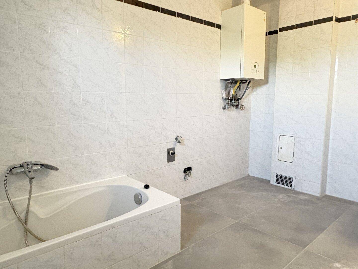 Geräumiges Badezimmer mit Badewanne und Gastherme an der Wand, funktional ausgestattet.