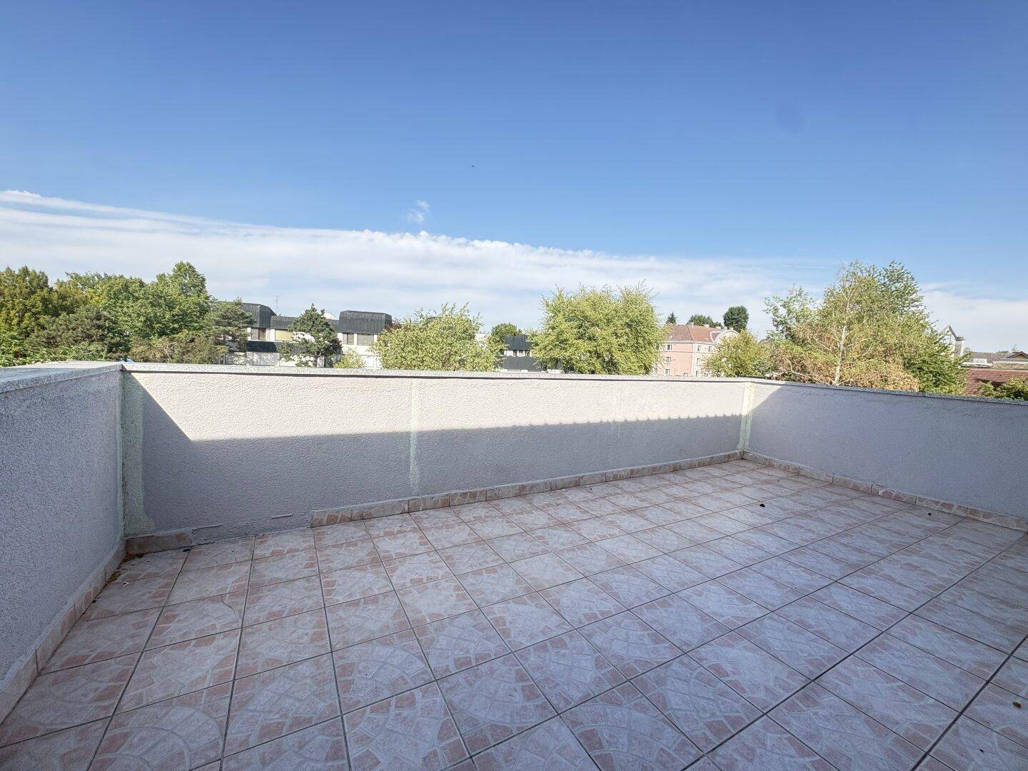 Große Dachterrasse mit Fliesenboden und weitem Blick über die Umgebung, ideal zum Entspannen.