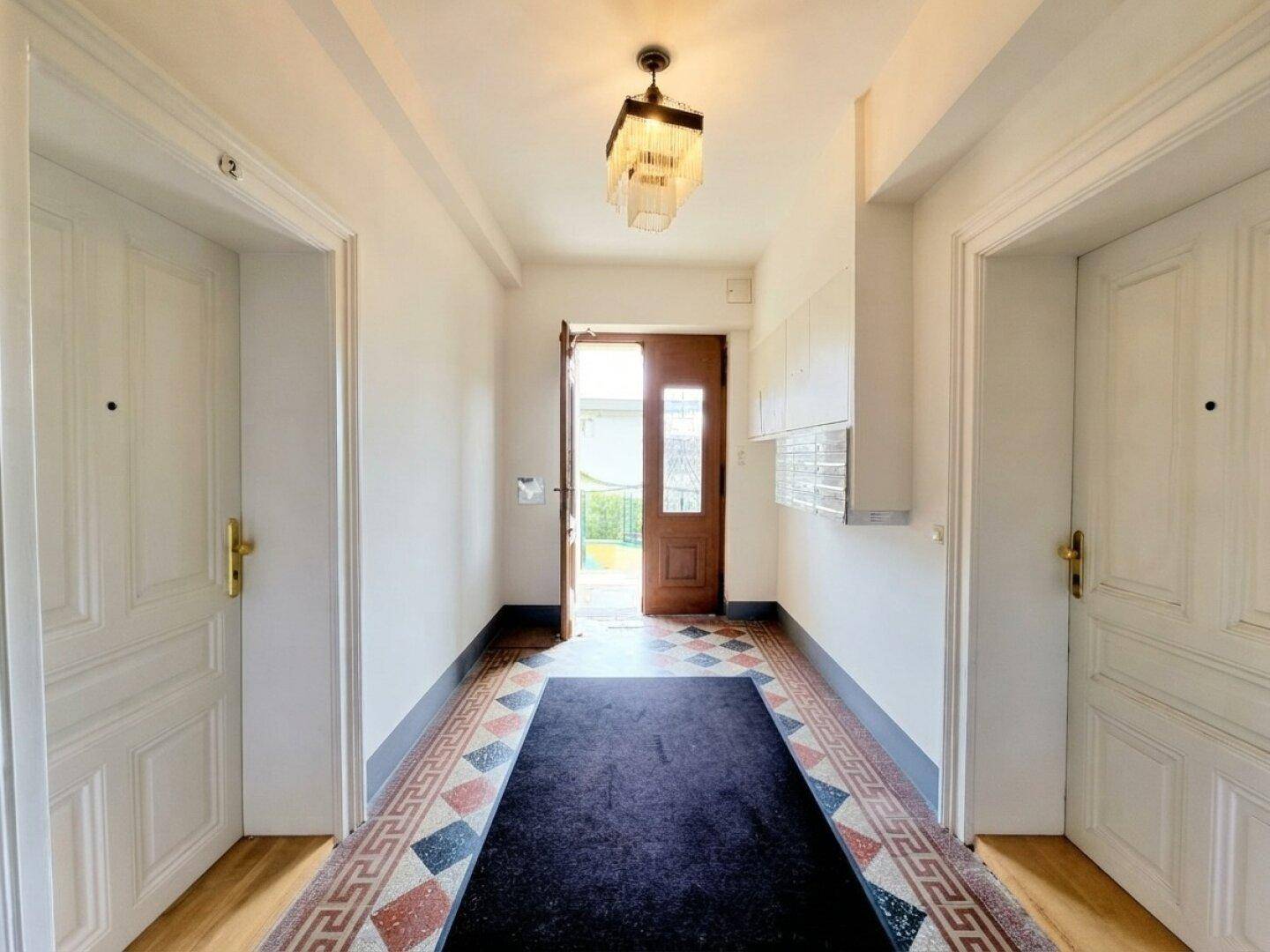 Heller Flur mit dekorativen Bodenfliesen und Zugang zu weiteren Räumen sowie einem Balkon.