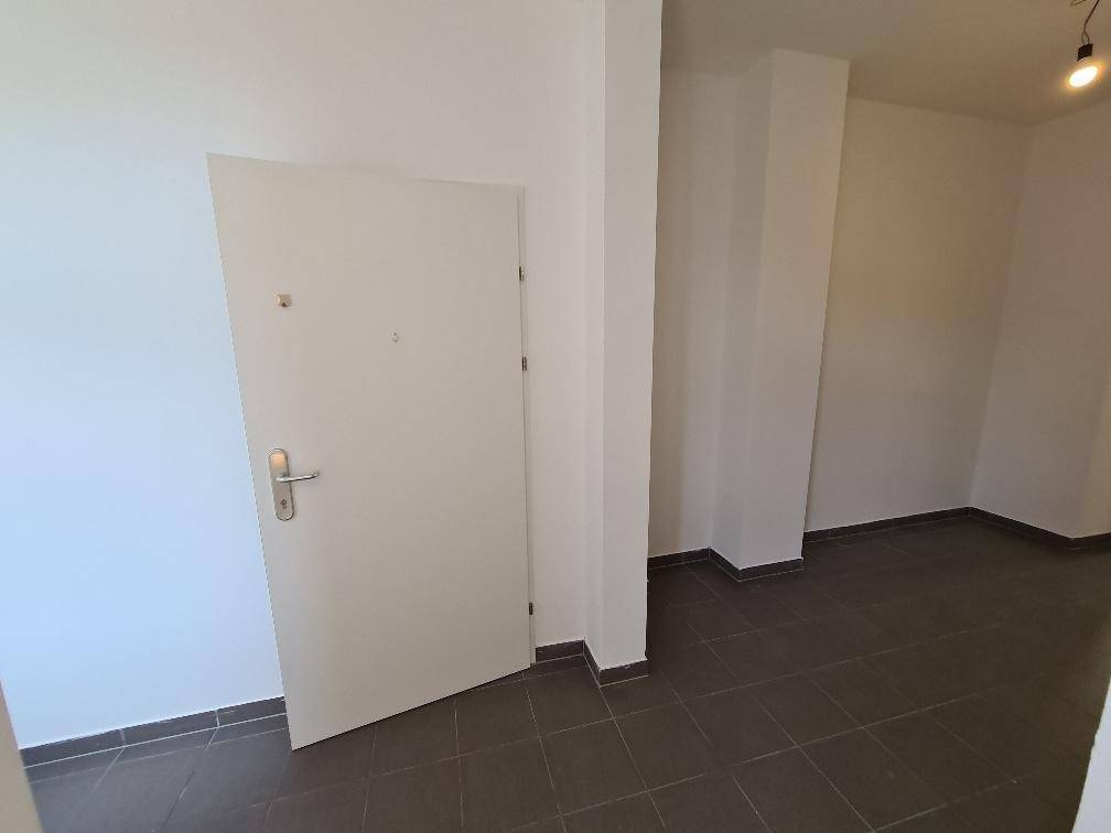 Eingangsbereich mit Fliesenboden und weißer Wohnungstür, hell und funktional gestaltet.