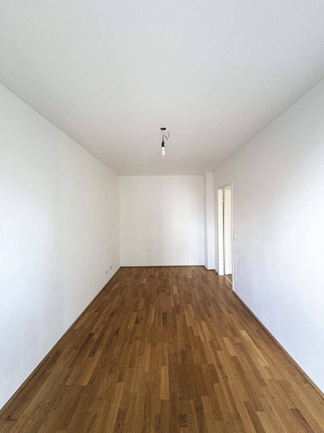 Langer, leerer Raum mit hellem Parkettboden und weißen Wänden, bereit zur individuellen Gestaltung.