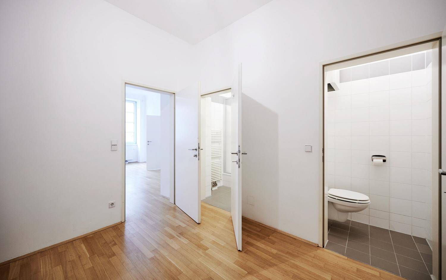 Flur mit Parkettboden und Zugang zu einem WC sowie weiteren Zimmern der Wohnung.