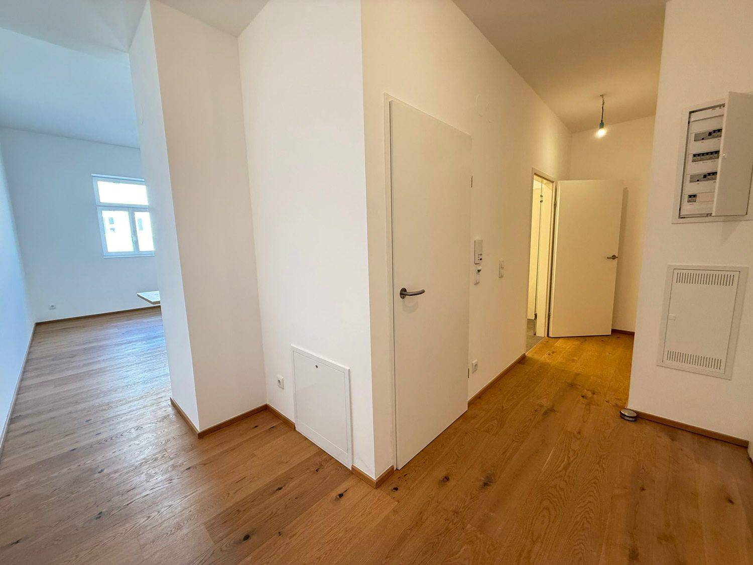 Geräumiger Flur mit Holzboden und Zugang zu verschiedenen Zimmern der Wohnung.