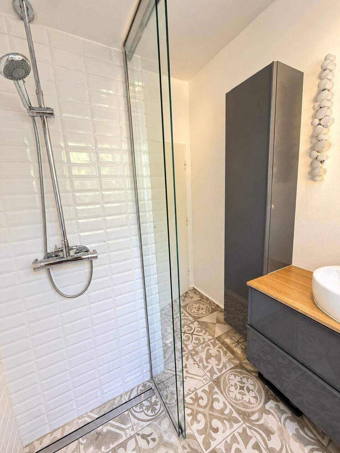 Elegantes Badezimmer mit großer begehbarer Dusche, modernem Waschtisch und stilvollen Fliesen.
