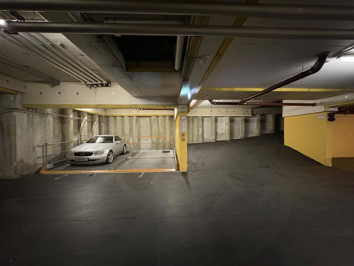 Tiefgarage mit einem Fahrzeug auf einem automatischen Parksystem und Betonwänden.