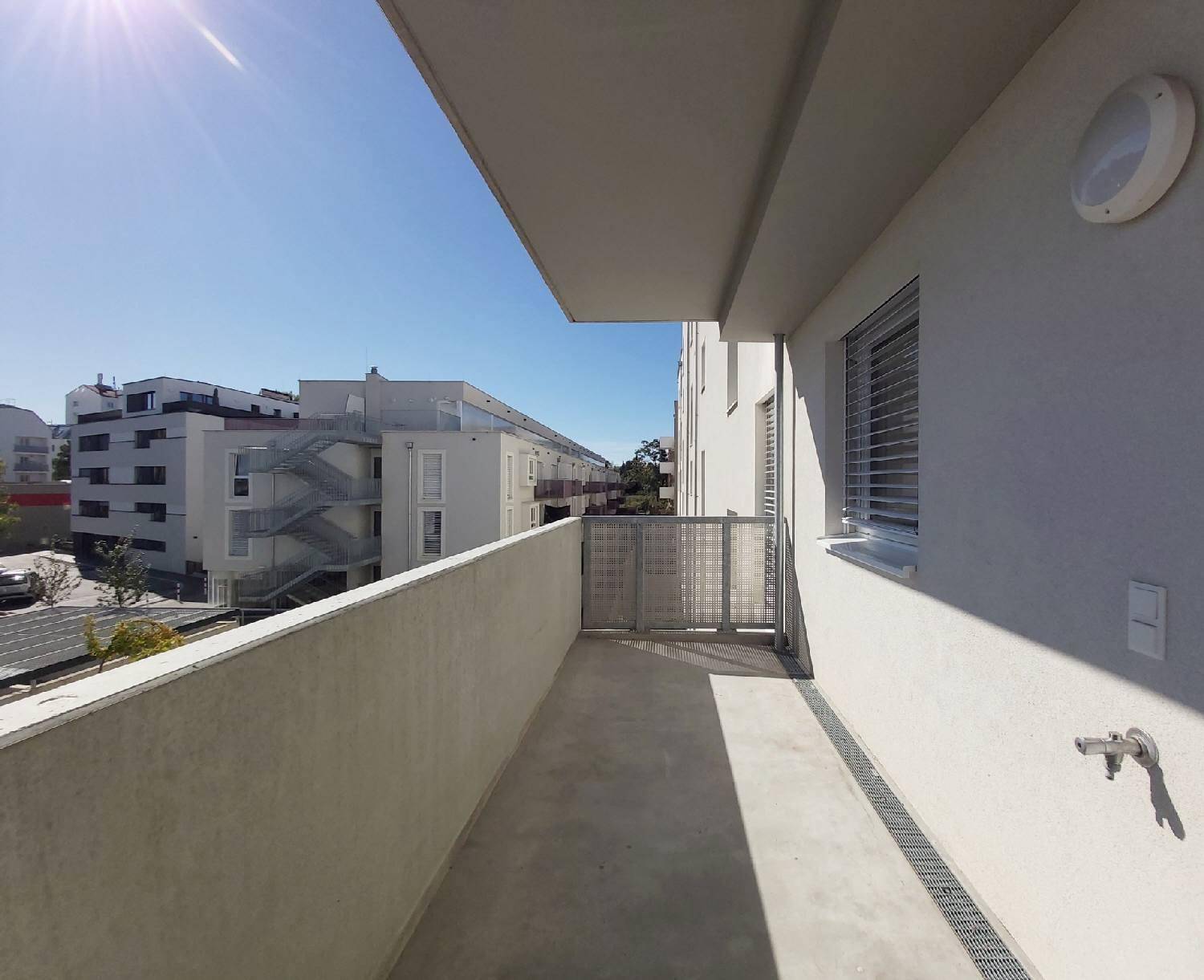 Sonniger Balkon mit Blick auf die umliegenden Wohngebäude und den blauen Himmel.