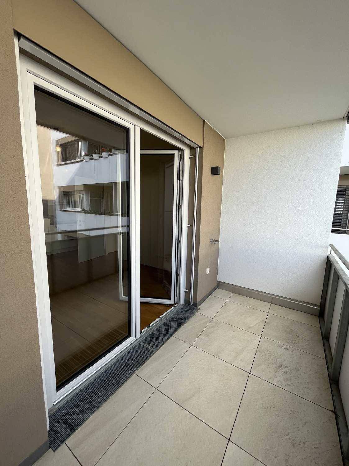 Heller Balkon mit Fliesenboden und Schiebetür, die zum Innenbereich der Wohnung führt.
