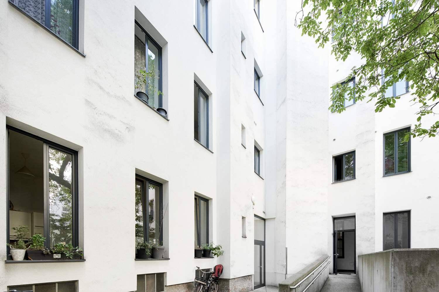 Heller Innenhof mit Rampe und Fenstern, die in die Wohnungen blicken.