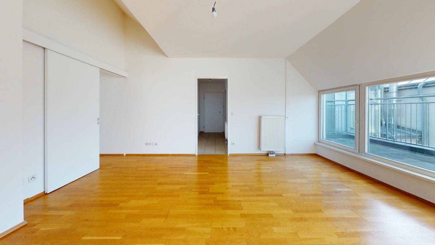 Geräumiger Wohnbereich mit Holzboden, Schiebetüren und großen Fenstern.