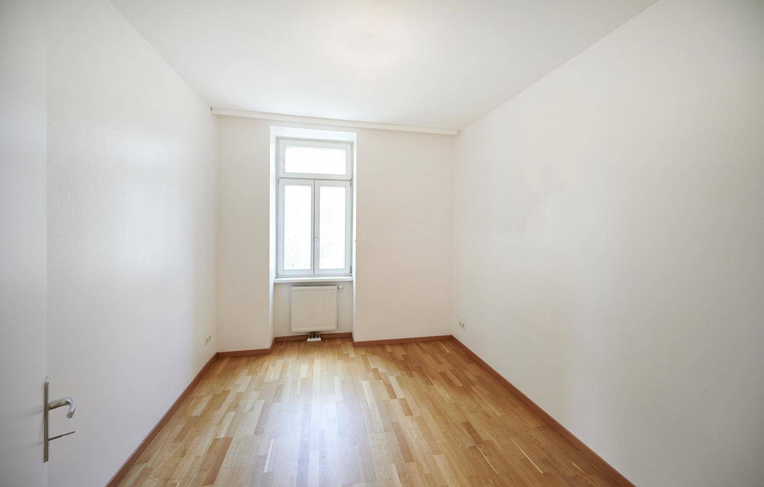 Kleines, helles Zimmer mit Parkettboden und einem Fenster, ideal als Schlaf- oder Arbeitszimmer.