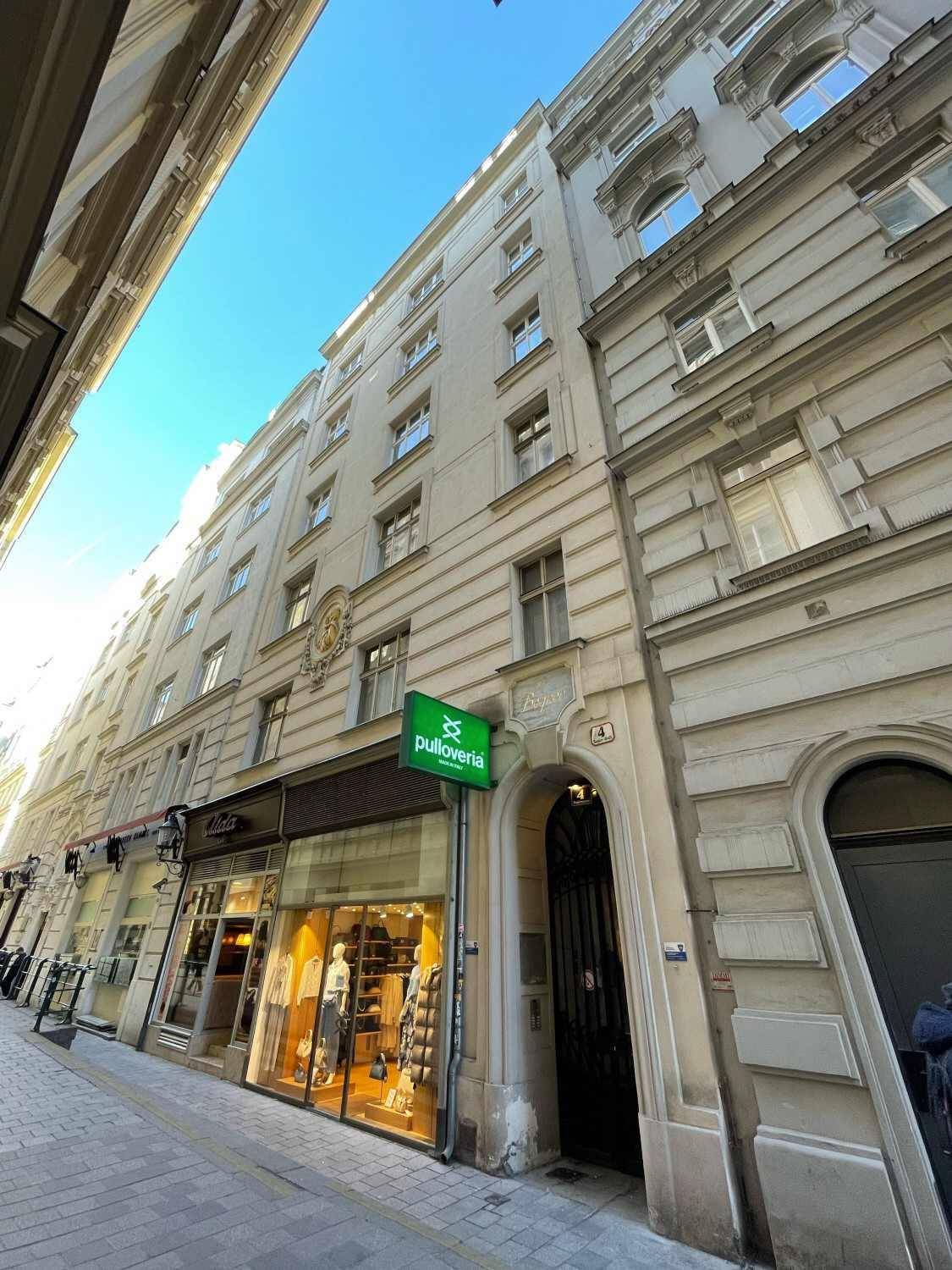 Historische Fassade eines Gebäudes mit Geschäften im Erdgeschoss und einem eleganten Eingangsbereich.