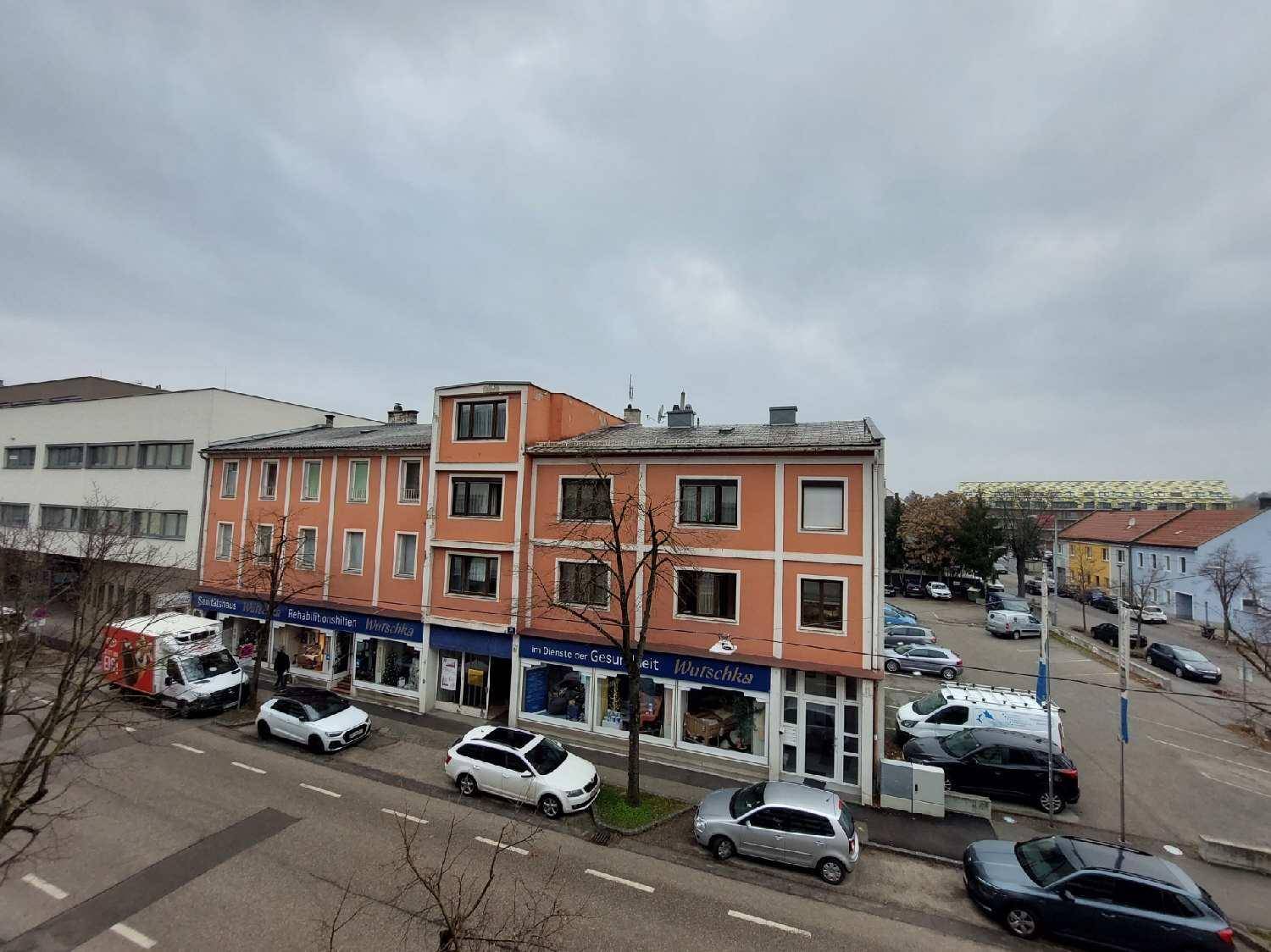 Straßenansicht mit mehrstöckigen Gebäuden und parkenden Autos.