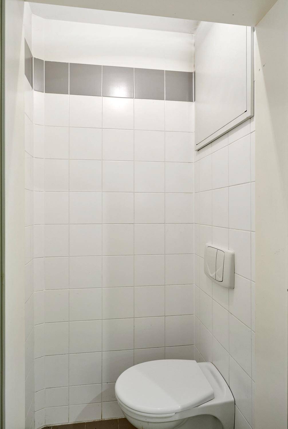Separates WC mit Wand-WC und weißen Fliesen, praktisch und sauber.