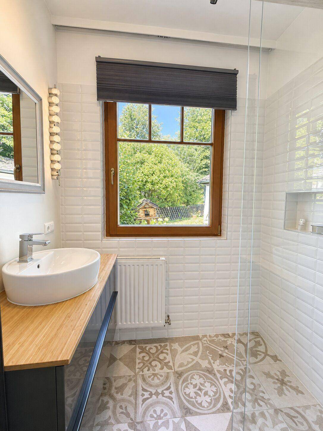 Modernes Badezimmer mit begehbarer Dusche, stilvollem Waschbecken und Fenster mit Grünblick.