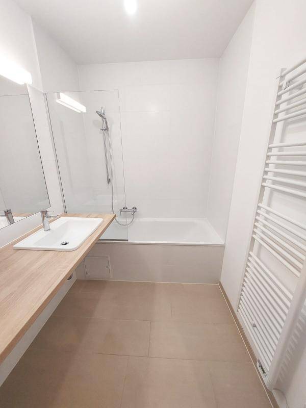 Modernes Badezimmer mit Badewanne, Duschfunktion, Einzelwaschbecken und beheiztem Handtuchhalter.