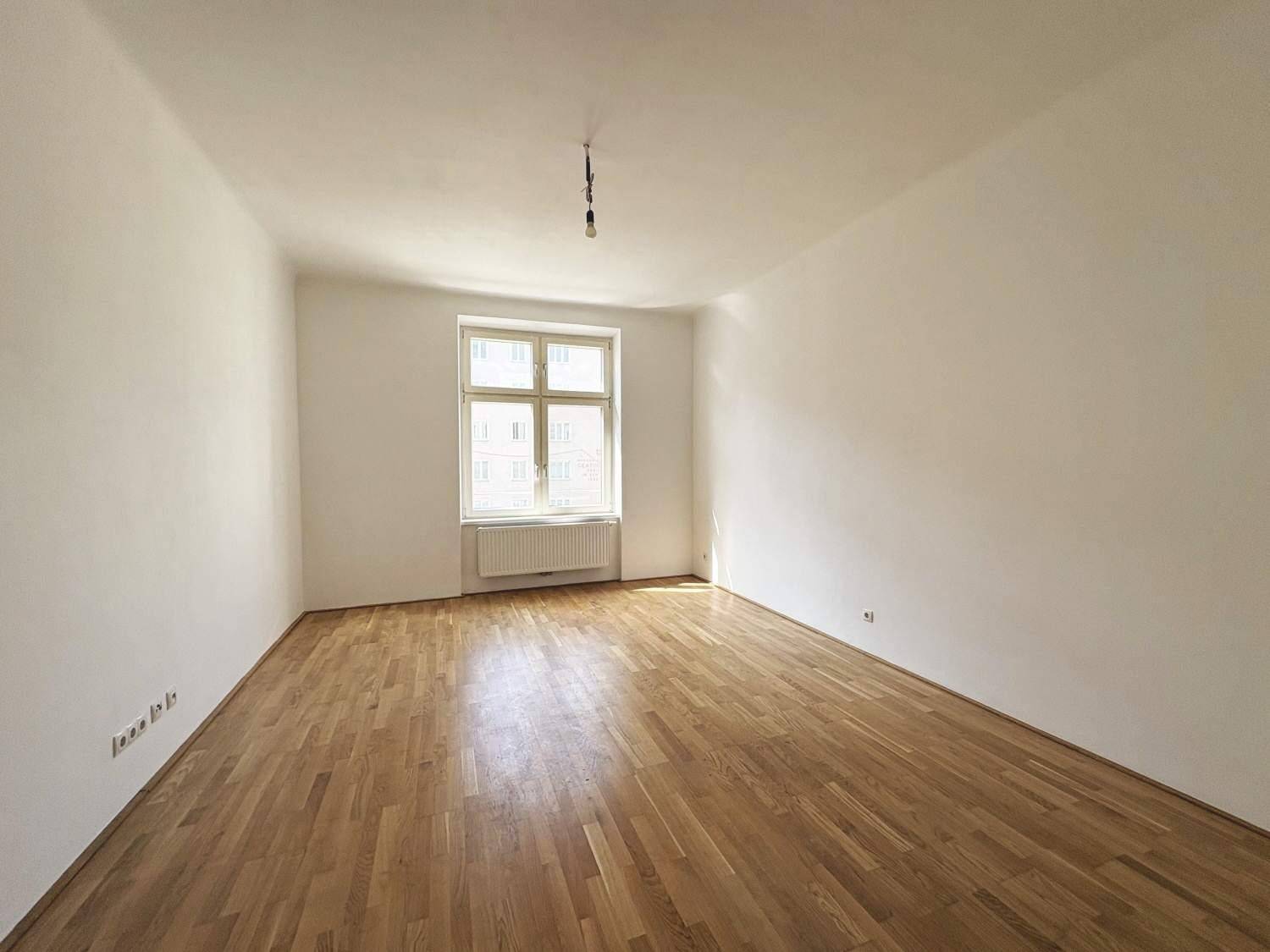 Lichtdurchfluteter Raum mit hellem Parkettboden und einem großen Fenster, bereit zur individuellen Gestaltung.