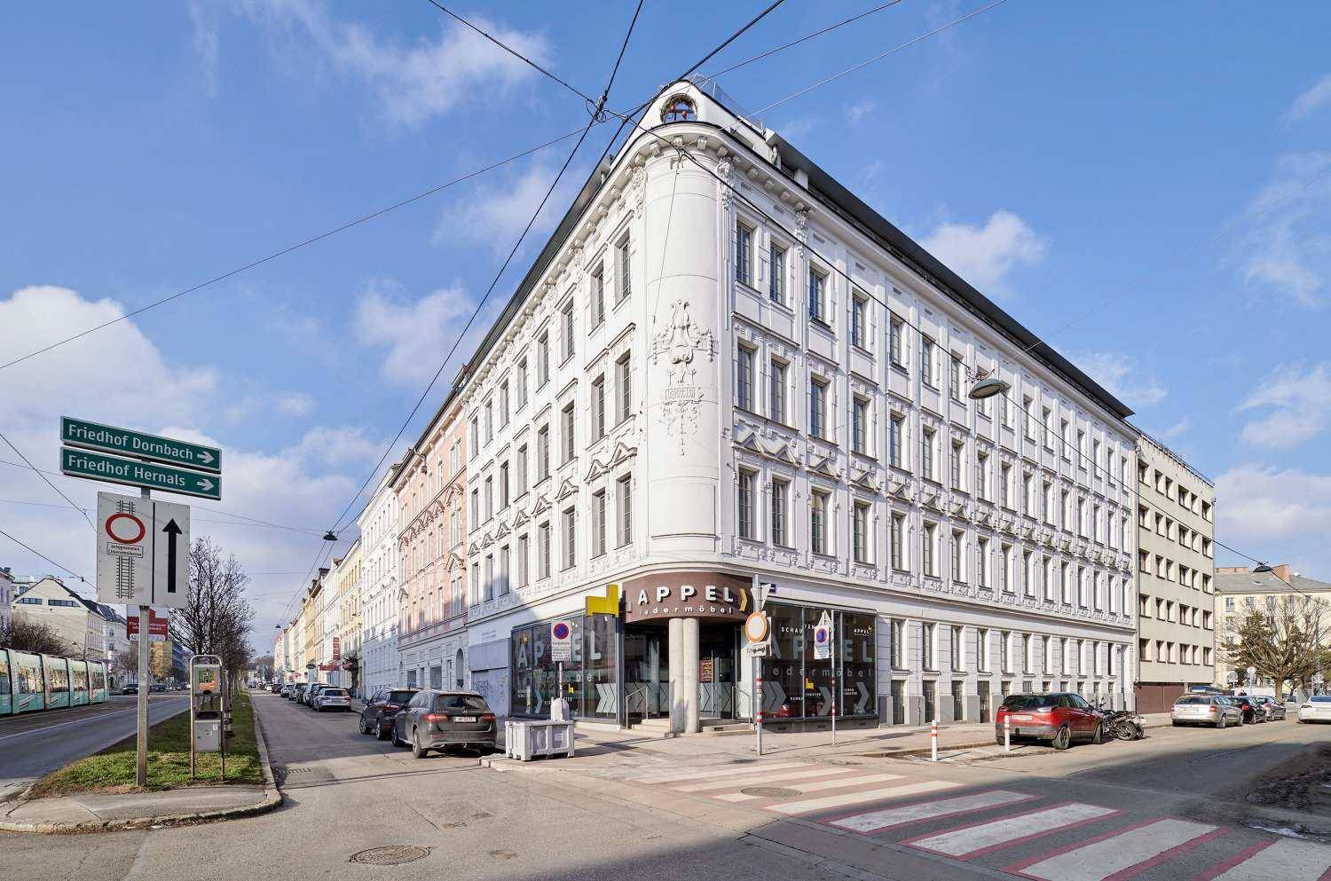 Historisches Eckgebäude in der Stadt mit klassischer Architektur und vielen Fenstern.
