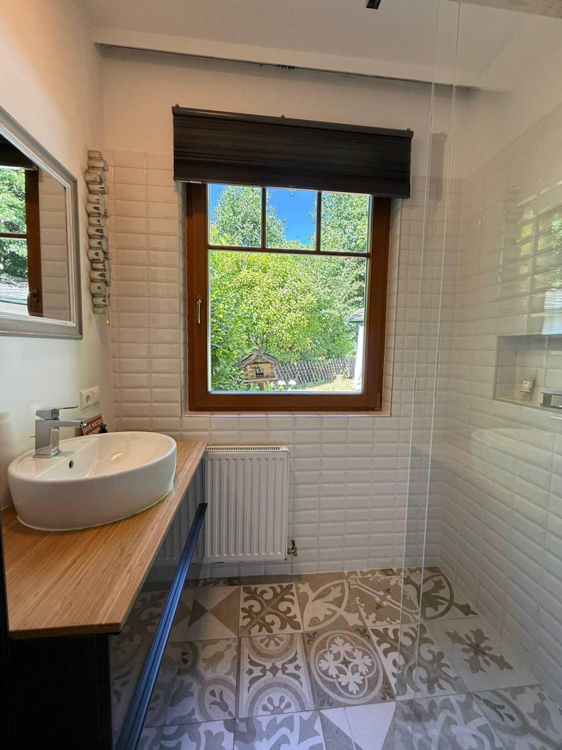 Modernes Badezimmer mit begehbarer Dusche, Einzelwaschbecken und gemusterten Fliesen.