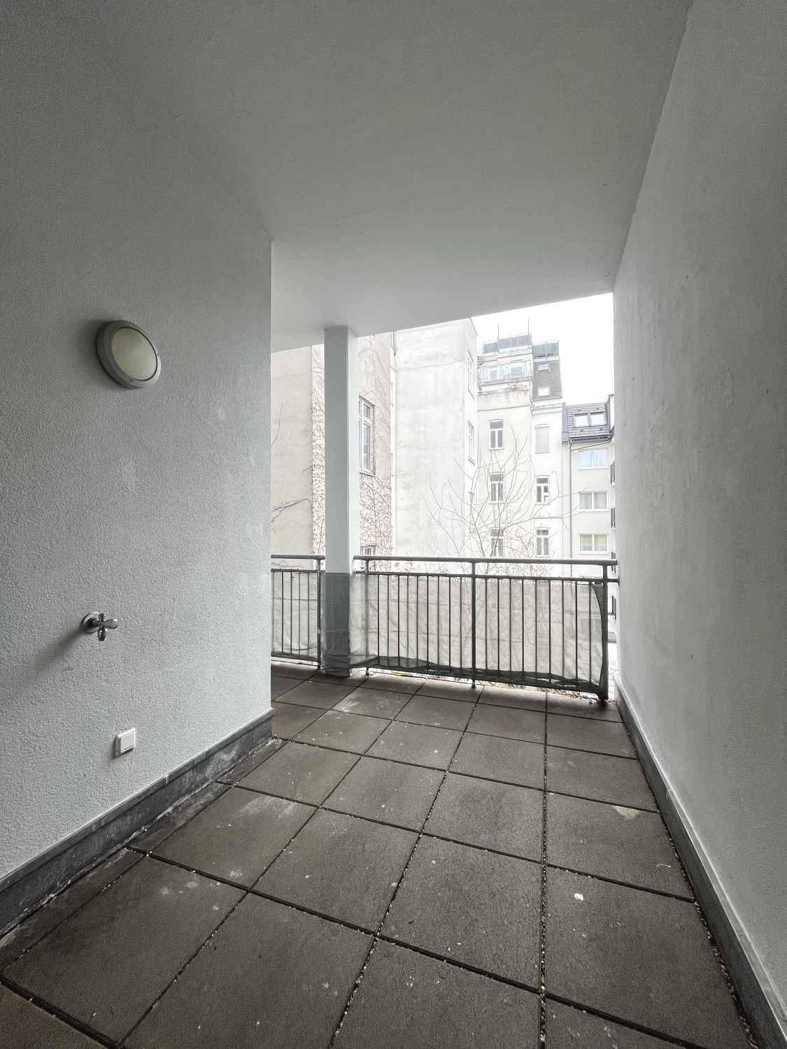 Überdachter Balkon mit Metallgeländer und Blick auf die städtische Umgebung.