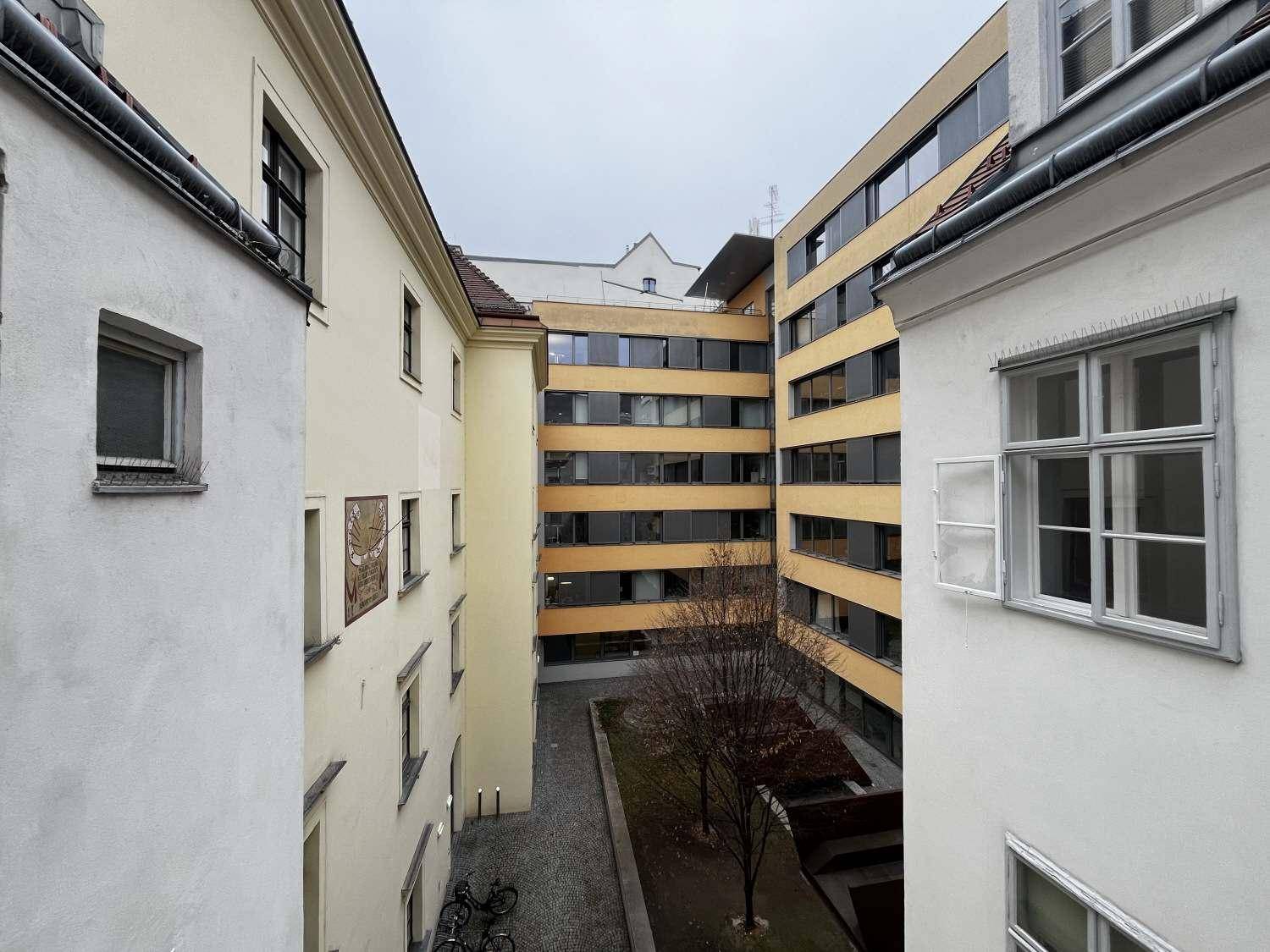 Blick von oben in einen Innenhof mit einer Mischung aus Alt- und Neubauten sowie einer kleinen Grünfläche.