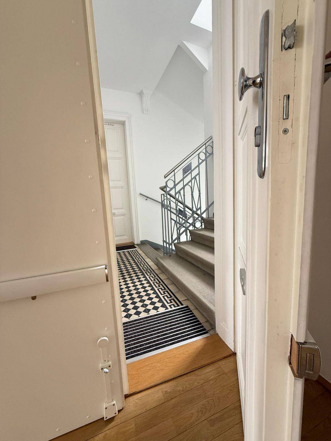 Eingangsbereich mit Treppe und dekorativem Teppich, der zu den oberen Etagen führt.