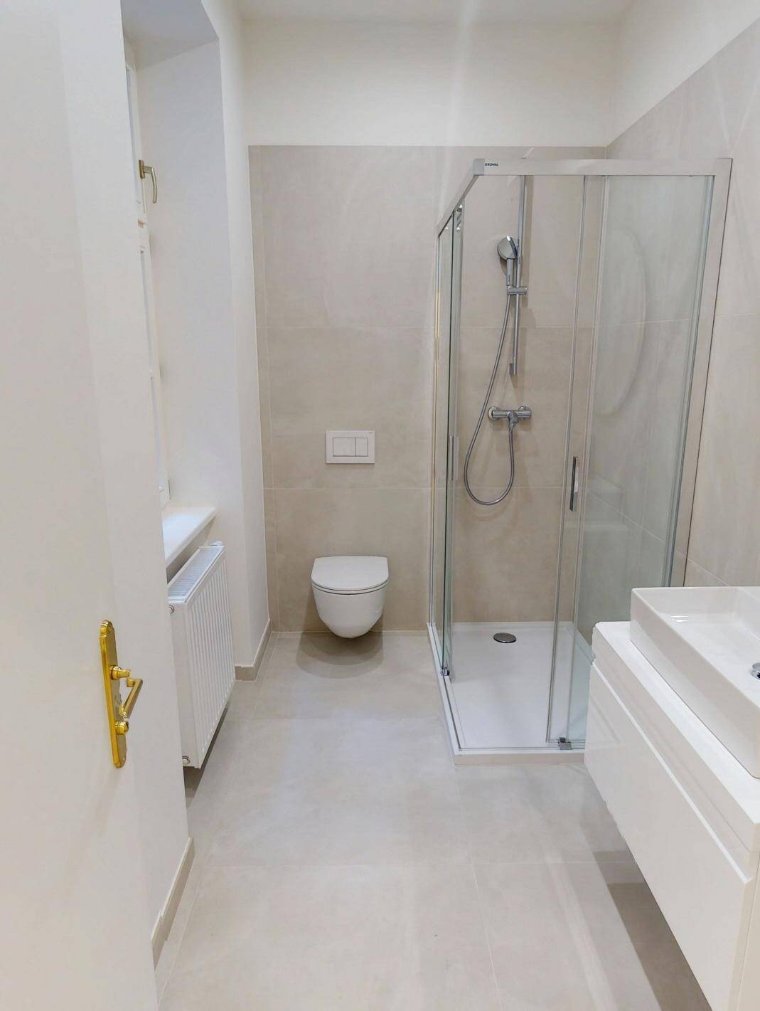 Modernes Badezimmer mit begehbarer Dusche, wandhängendem WC und eleganten beigefarbenen Fliesen.