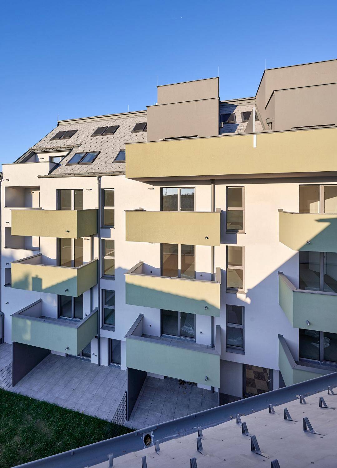 Fassade eines modernen Wohngebäudes mit zahlreichen Balkonen und Dachfenstern.