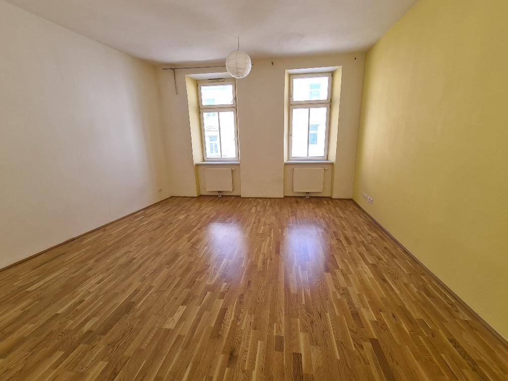 Heller Raum mit Holzboden und zwei Fenstern, bereit zur individuellen Gestaltung.