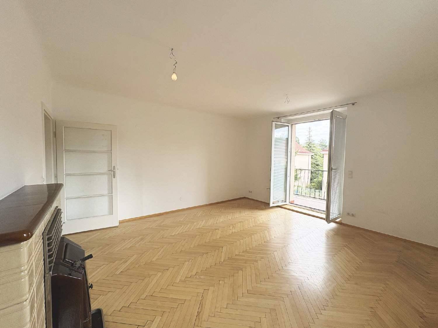 Geräumiges Wohnzimmer mit Fischgrätparkett und Zugang zu einem Balkon.