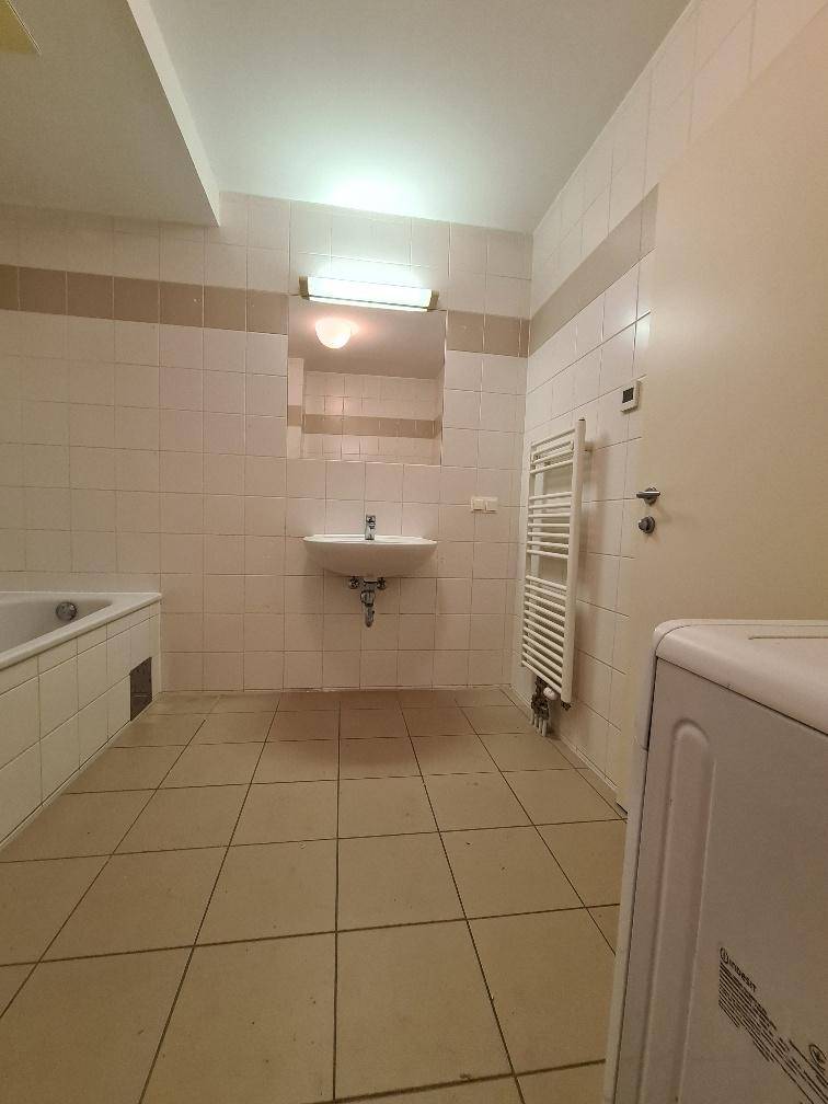 Gefliestes Badezimmer mit Badewanne, Waschbecken und einem praktischen Handtuchheizkörper.