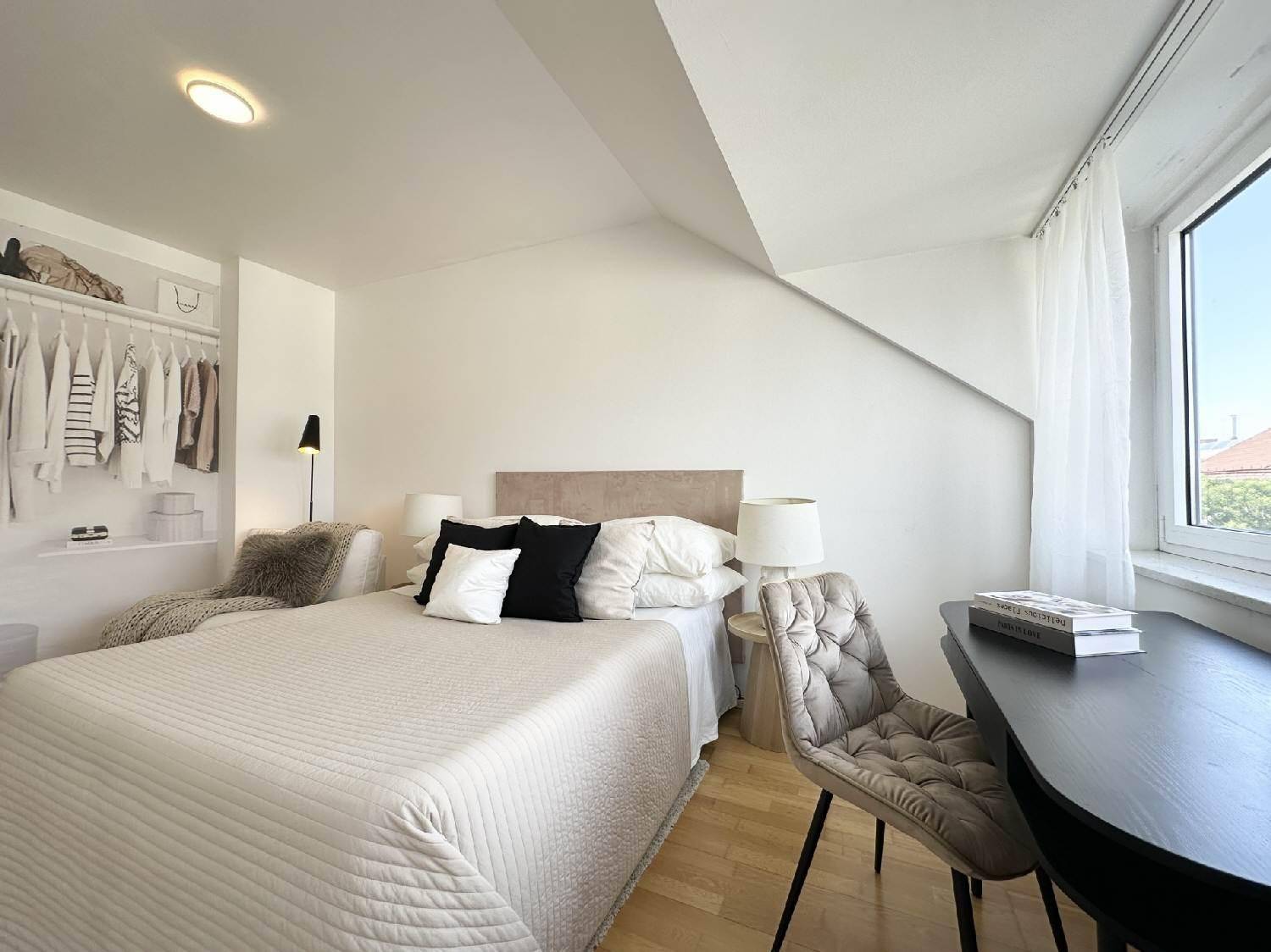 Gemütliches Schlafzimmer mit Holzboden, Schreibtisch und offenem Kleiderschrankbereich.