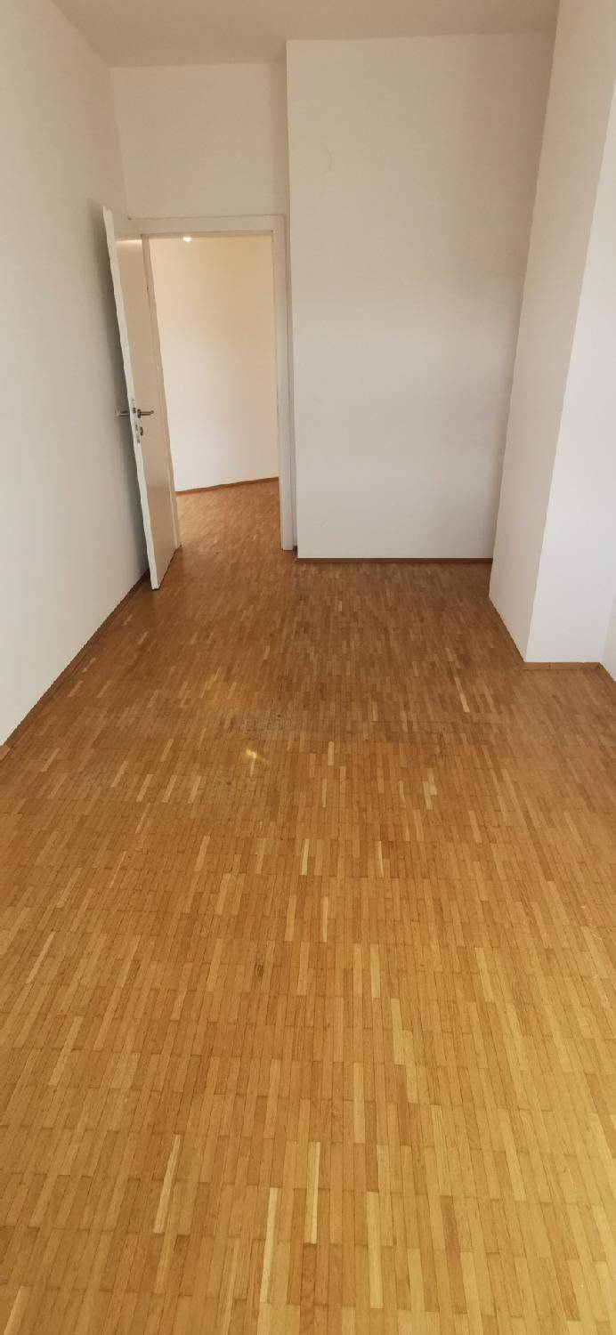 Helles Zimmer mit Holzparkett und weiß gestrichenen Wänden, bietet eine ruhige und neutrale Basis.