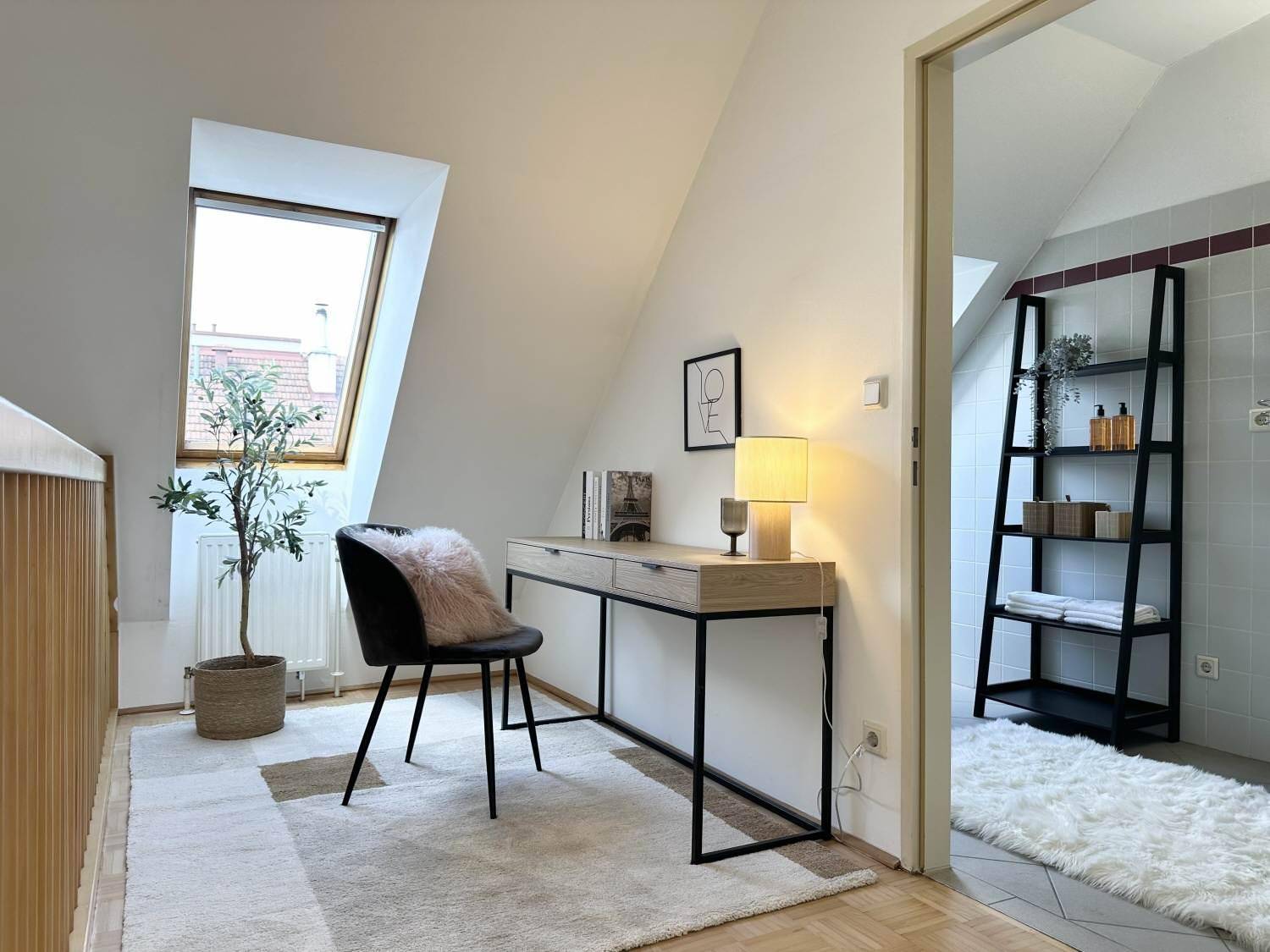 Helles Arbeitszimmer im Dachgeschoss mit Schreibtisch, Dachfenster und Teppichboden.