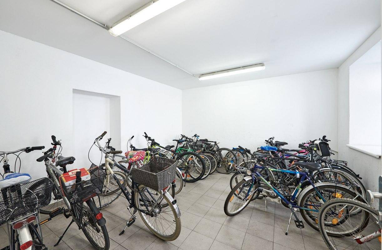 Geräumiger Fahrradraum im Kellergeschoss mit zahlreichen abgestellten Fahrrädern und Fliesenboden.