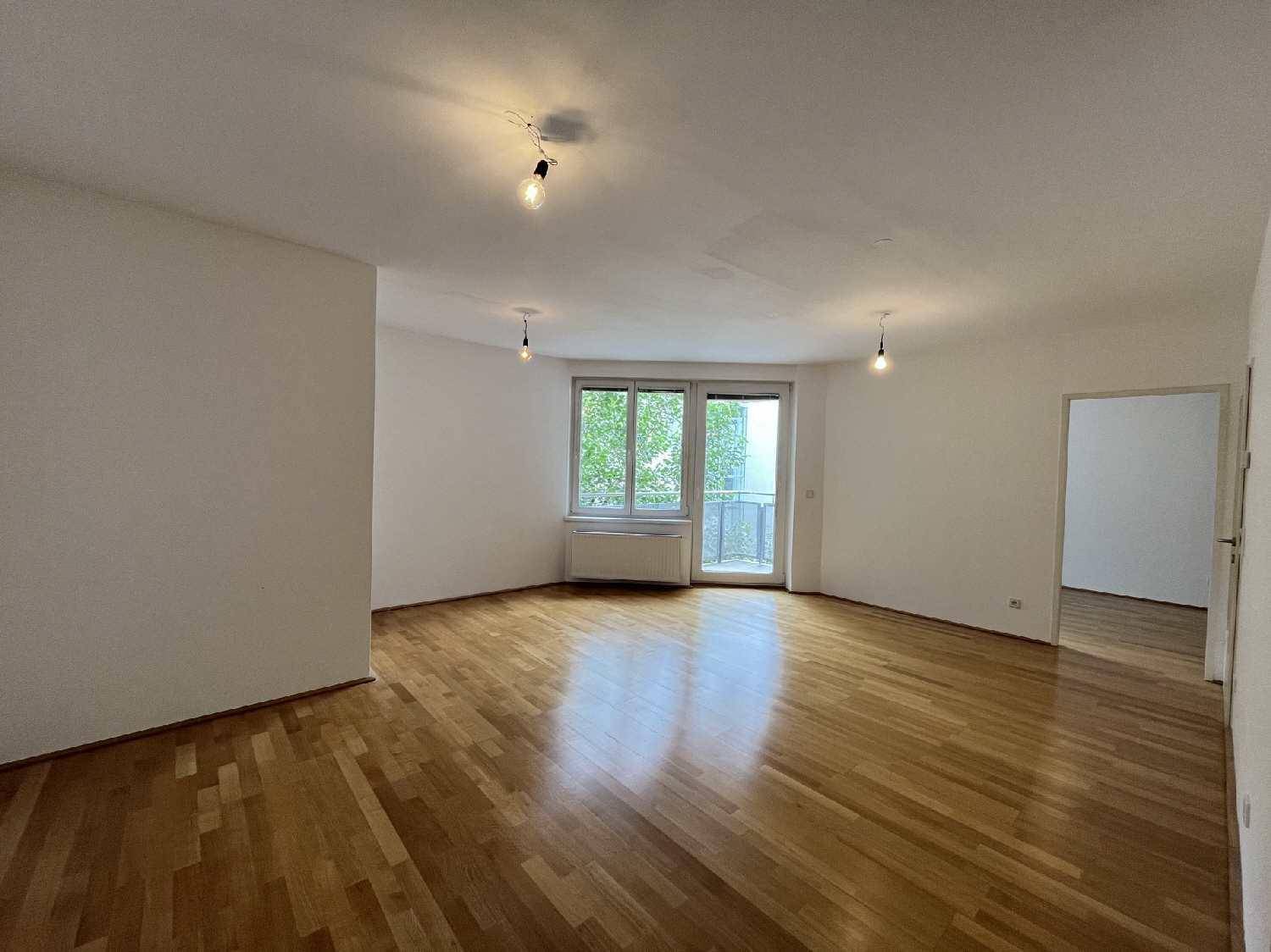 Heller Wohnraum mit Parkettboden und Zugang zu einem Balkon, ideal für gemütliche Stunden.