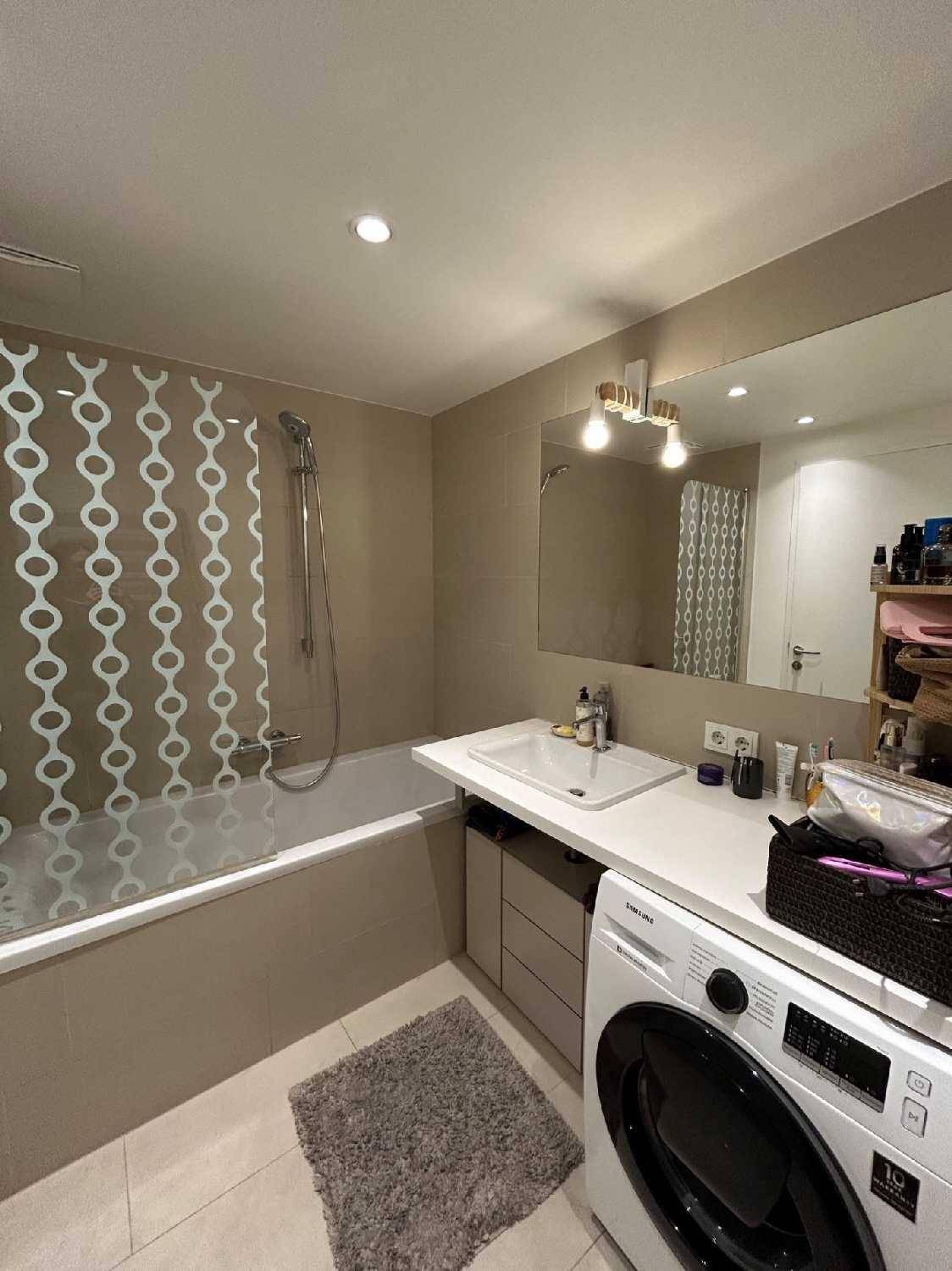 Modernes Badezimmer mit Badewanne, Dusche, Waschbecken und integrierter Waschmaschine.