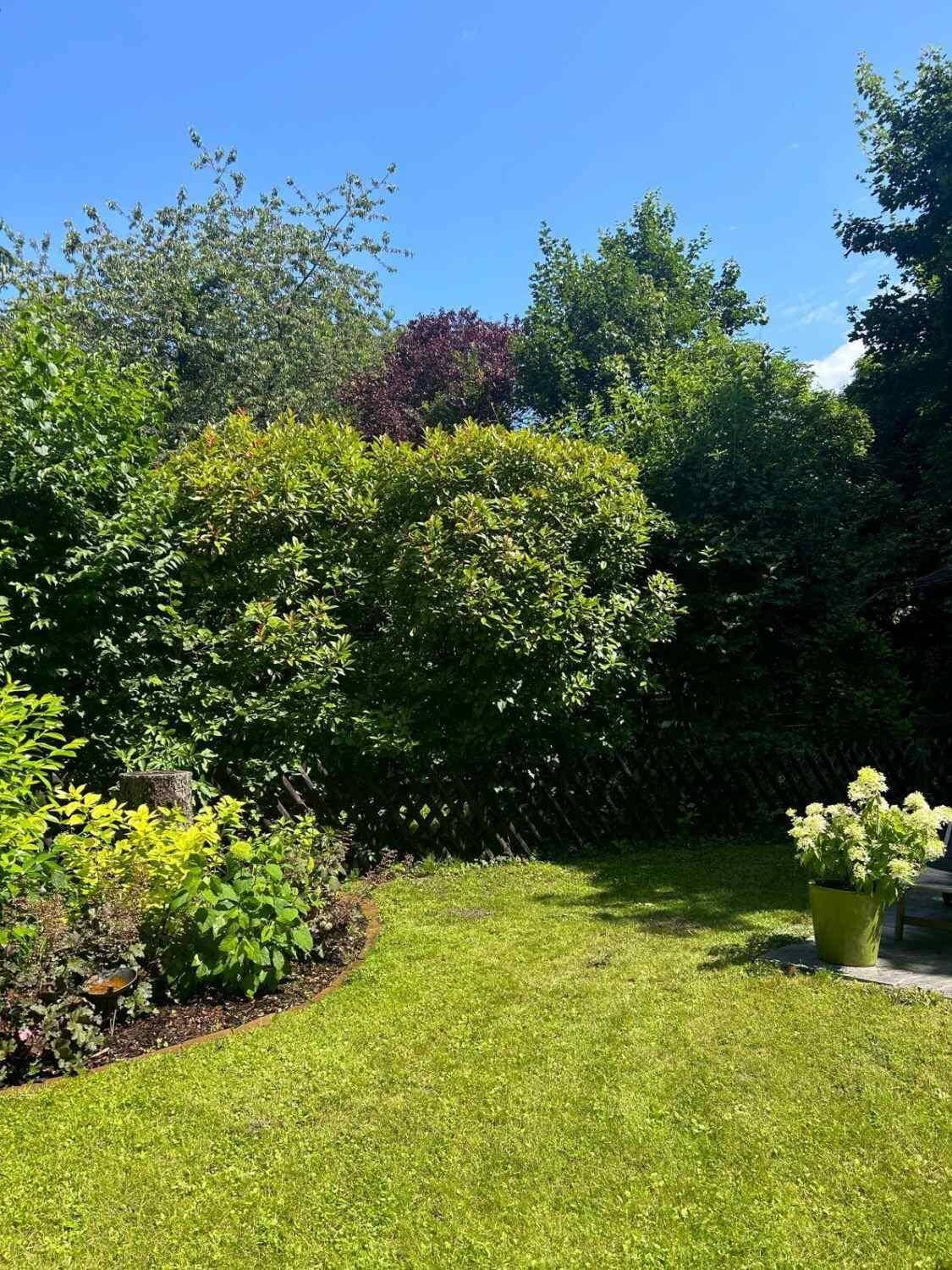Gepflegter Garten mit Rasenfläche, Blumenbeeten und üppiger Bepflanzung.