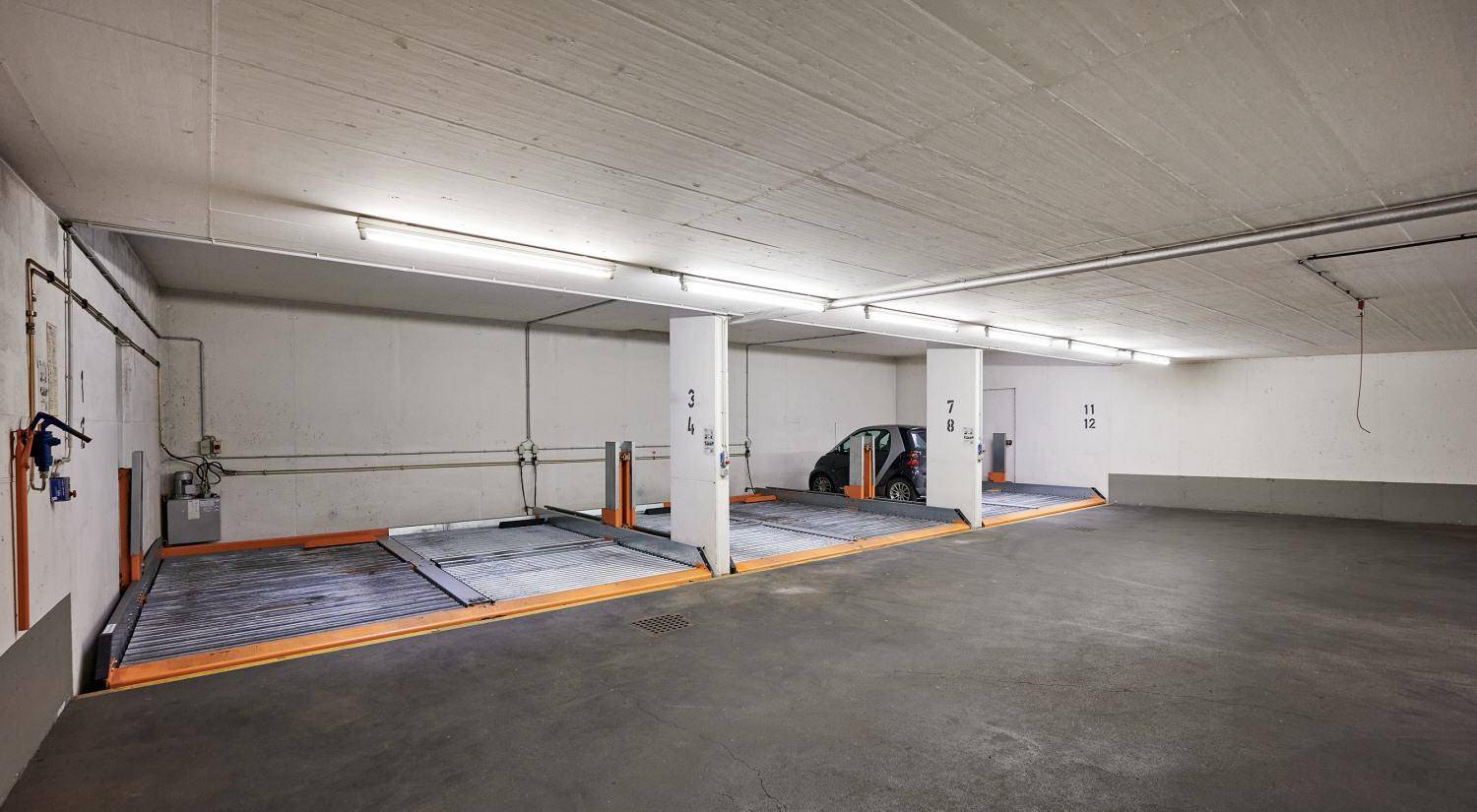 Tiefgarage mit automatischen Parksystemen und Betonboden für mehrere Fahrzeuge.