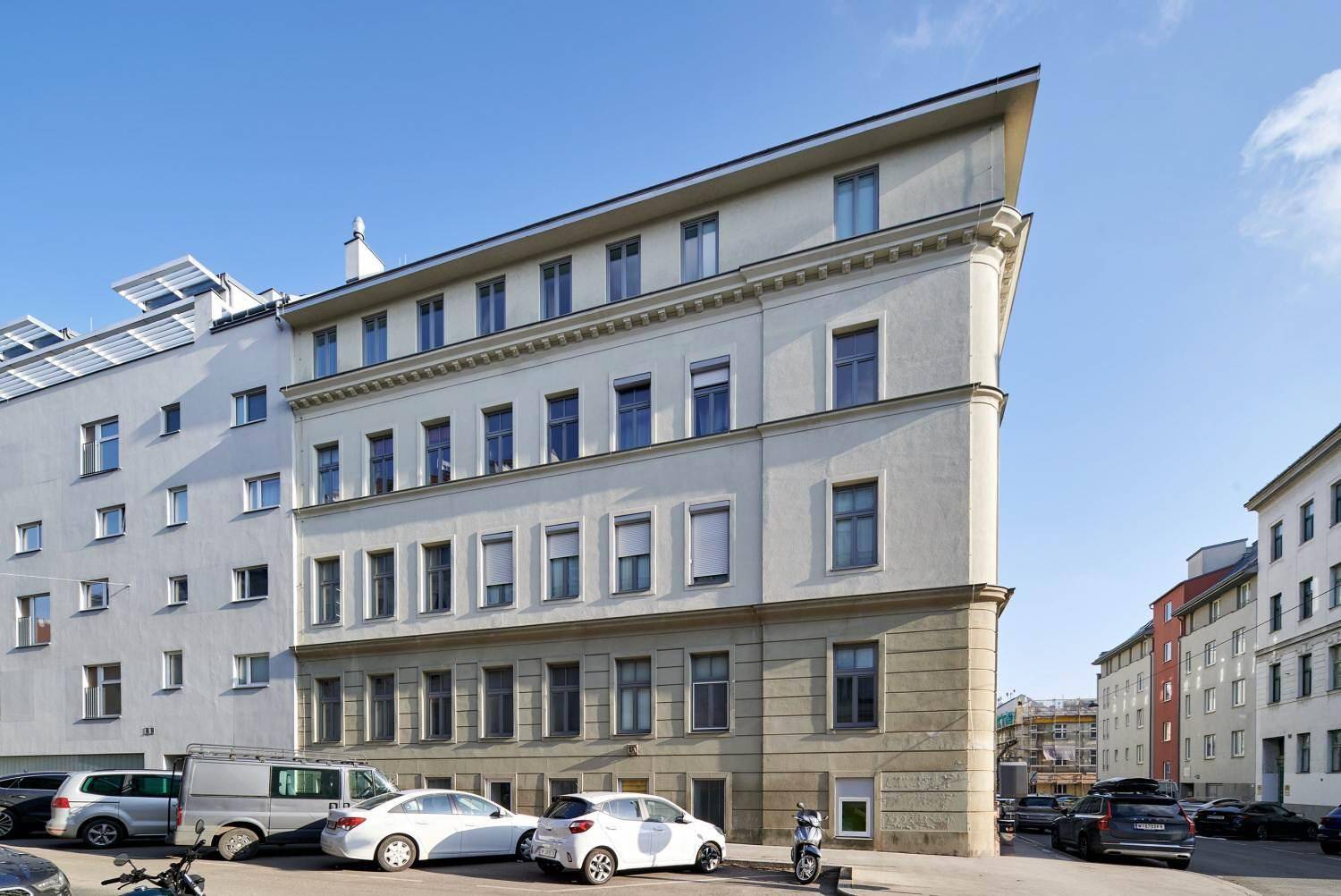 Seitenansicht eines Gebäudes mit moderner Architektur, vielen Fenstern und klarem Himmel.