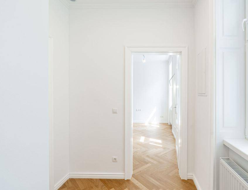 Heller Flur mit Fischgrätparkett, der zu weiteren lichtdurchfluteten Räumen führt.
