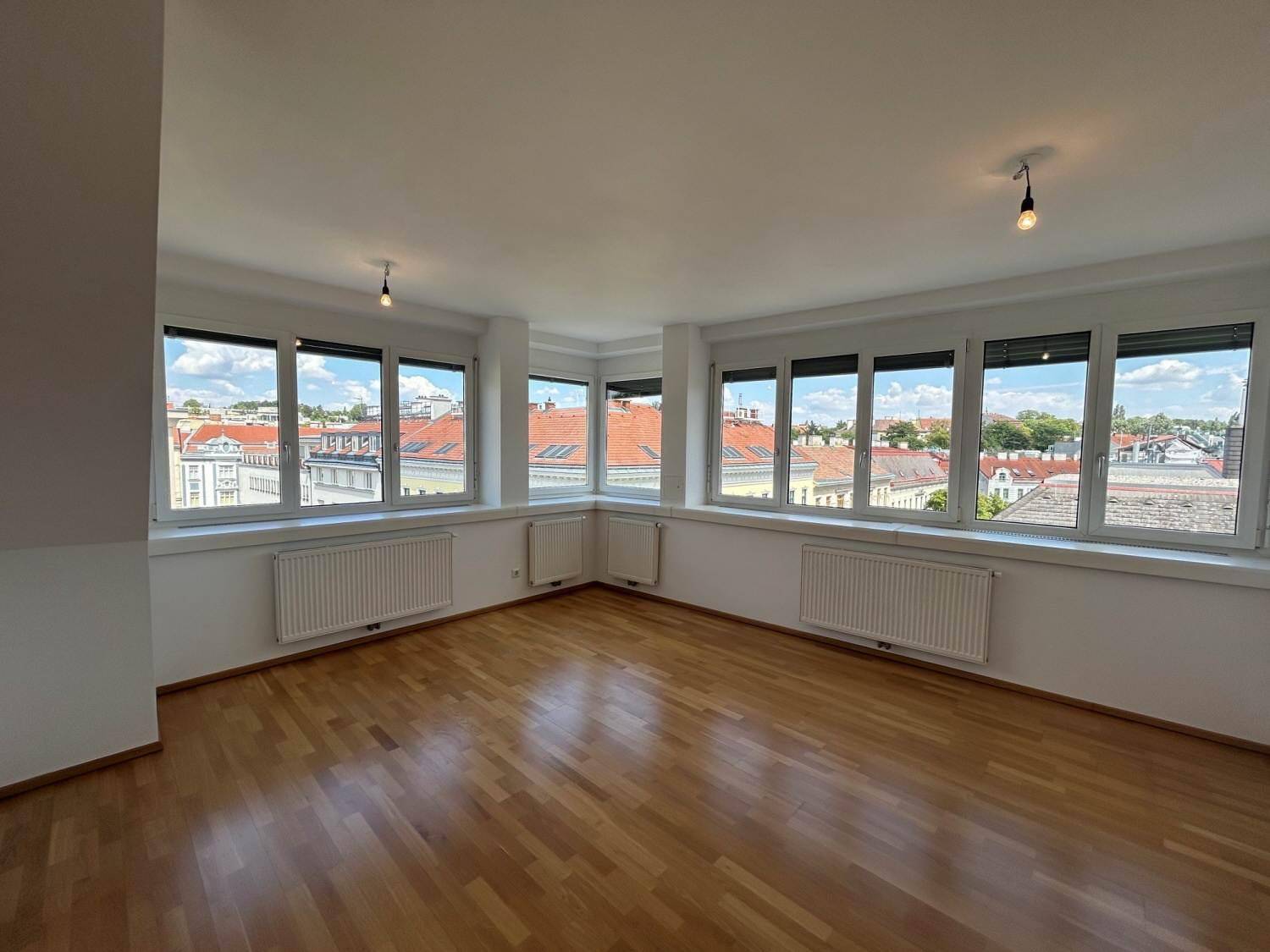Geräumiges Wohnzimmer mit Parkettboden und weitem Blick über die Stadt.