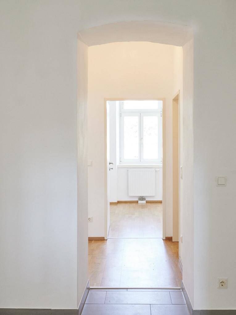 Heller Flur mit Fliesenboden und einem Bogen, der zu einem weiteren Raum führt.