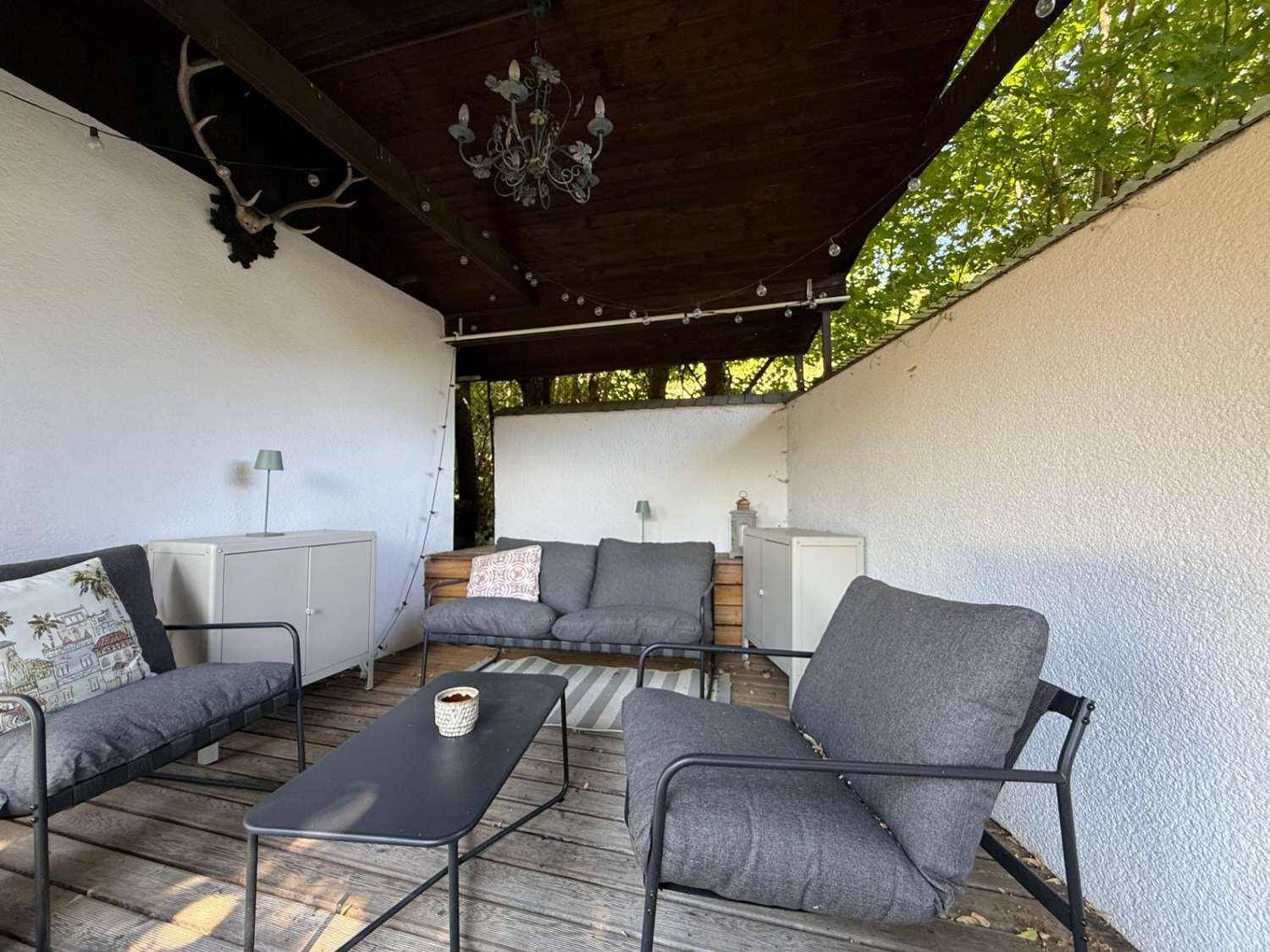 Überdachte Terrasse mit bequemen Loungemöbeln und Hirschgeweih-Dekoration.