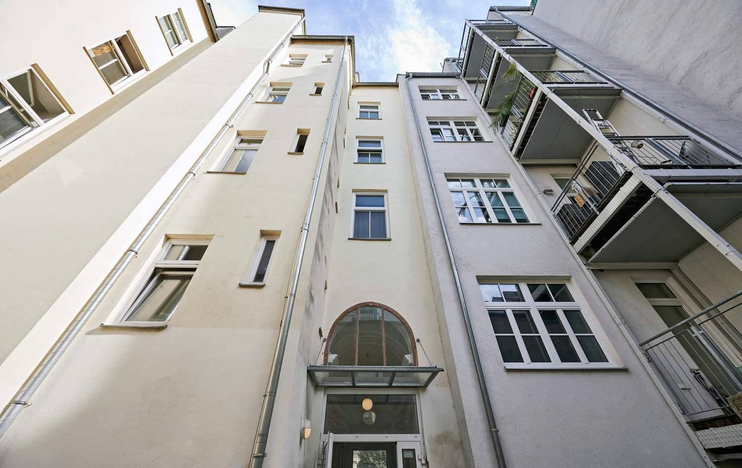 Innenhofansicht eines Mehrfamilienhauses mit mehreren Etagen und Balkonen.