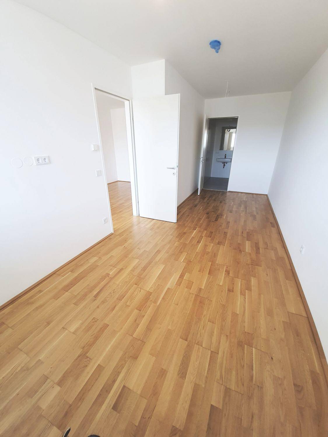 Helles Zimmer mit Parkettboden und weißen Wänden, das vielseitig als Schlaf- oder Arbeitszimmer genutzt werden kann.