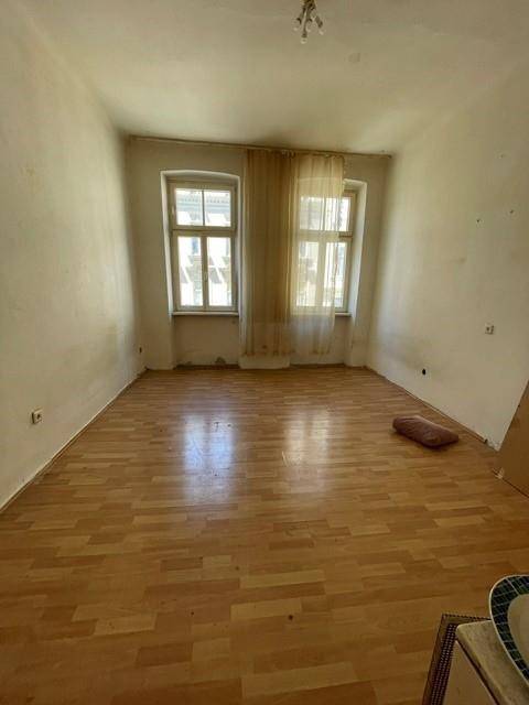 Heller Wohnraum mit Laminatboden und zwei Fenstern, bereit zur individuellen Gestaltung.