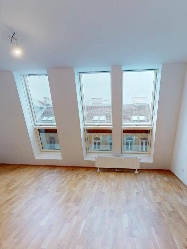 Lichtdurchfluteter Dachgeschossraum mit Holzboden und Blick auf die Umgebung.